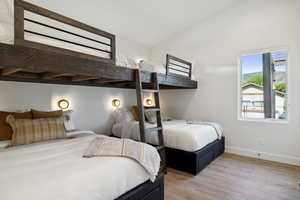 Bedroom with light hardwood / wood-style floors and lofted ceiling