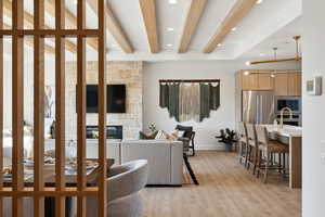 Living room featuring a fireplace, beam ceiling, and light hardwood / wood-style flooring