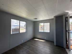 Unfurnished room featuring dark hardwood / wood-style flooring and a textured ceiling