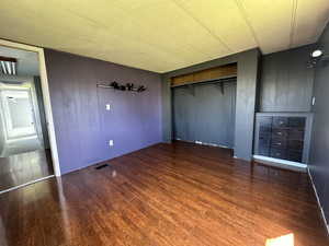 Unfurnished bedroom with dark wood-type flooring and a closet