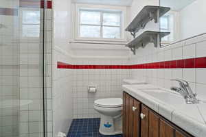 Bathroom featuring tile flooring, tile walls, toilet, and vanity