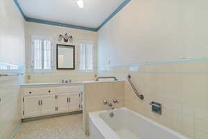 Bathroom featuring tile flooring, tile walls, a bathtub, and large vanity