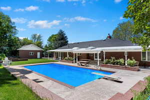 View of swimming pool featuring a patio area, a diving board, and a lawn