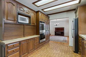 Kitchen with stainless steel appliances, an inviting chandelier, crown molding, and pendant lighting