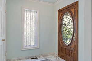 Entrance foyer featuring ornamental molding and a wealth of natural light