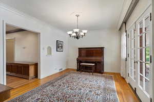 Interior space featuring a chandelier, wood-type flooring, and crown molding