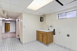 Laundry area with sink and light tile flooring