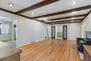 Living room featuring beamed ceiling, french doors, and light wood-type flooring