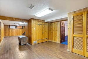 Basement with wooden walls, hardwood floors, and a textured ceiling