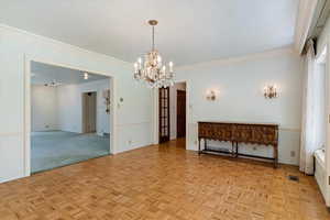 Dining area featuring ornamental molding, a chandelier, and light parquet floors