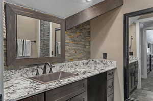 Interior space featuring dark brown cabinetry, sink, light stone counters, and carpet flooring