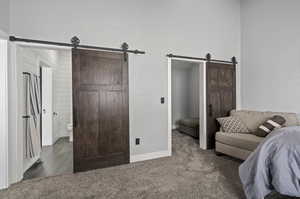 Carpeted bedroom with a barn door and ensuite bathroom