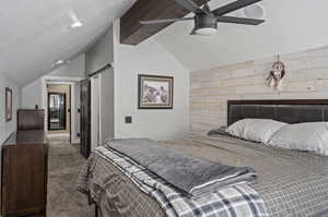 Carpeted bedroom featuring a barn door, ceiling fan, and lofted ceiling