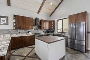 Kitchen featuring wall chimney range hood, stainless steel appliances, backsplash, dark tile flooring, and wood ceiling