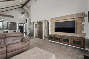 Living room with a barn door, high vaulted ceiling, carpet floors, and wooden ceiling