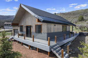 View of homes exterior with a deck and 2 car garage.