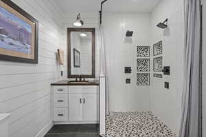 Bathroom featuring a shower with curtain, wooden walls, and large vanity