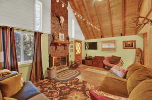 Living room with a fireplace, hardwood / wood-style flooring, wood ceiling, high vaulted ceiling, and beamed ceiling