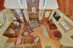 Living room with a high ceiling, hardwood / wood-style floors, and a large fireplace