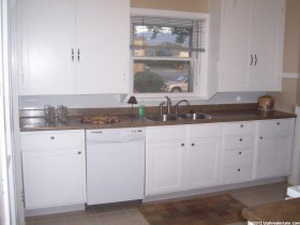 Kitchen featuring sink, white cabinets, and white dishwasher