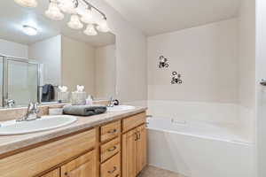 Bathroom with dual sinks, plus walk in shower, tile floors, and large vanity