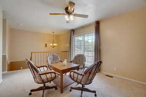 Dining area featuring ceiling fan with notable chandelier and light colored carpet