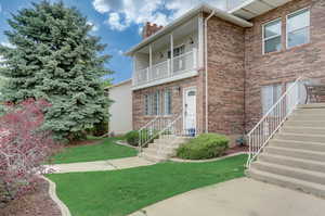 View of front of property featuring a front yard and a balcony