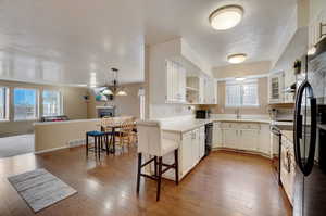 Kitchen with hanging light fixtures, white cabinets, hardwood / wood-style flooring, range with electric cooktop, and dishwasher