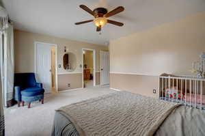 Carpeted bedroom featuring ceiling fan and ensuite bath