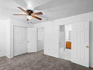 Unfurnished bedroom featuring ceiling fan, connected bathroom, light colored carpet, and a closet