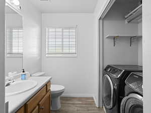 Bathroom featuring toilet, washer and clothes dryer, vanity, and wood-type flooring