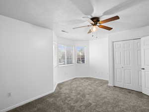 Unfurnished bedroom with carpet floors, ceiling fan, and a textured ceiling