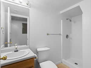 Bathroom featuring toilet, tile patterned flooring, vanity, electric panel, and a shower