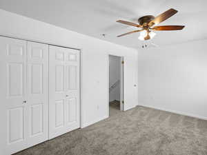 Unfurnished bedroom featuring carpet floors, ceiling fan, and a closet