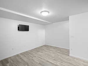 Basement featuring a textured ceiling and wood-type flooring