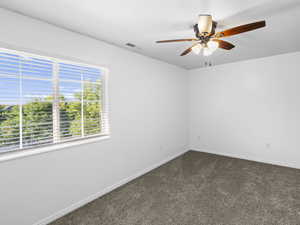 Empty room featuring ceiling fan and carpet flooring