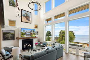 EXAMPLE Of  Living room featuring a towering ceiling, wood-type flooring, a water view, and an inviting chandelier