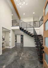 EXAMPLE Of Entrance foyer featuring beamed ceiling, a high ceiling, and an inviting chandelier