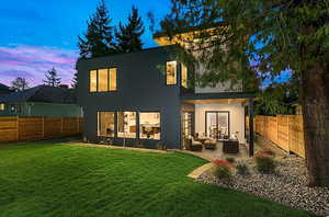 EXAMPLE Of  Back house at dusk featuring a patio, an outdoor hangout area, and a lawn