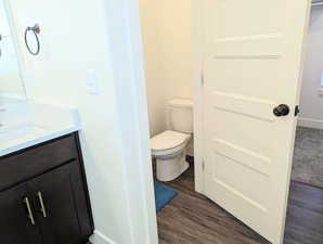 Bathroom with hardwood / wood-style flooring, vanity, and toilet