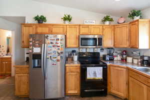 Kitchen with stainless steel appliances, sink, tile floors, and lofted ceiling