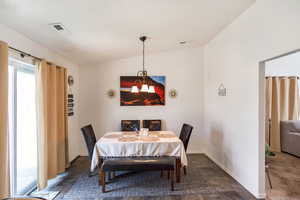 Carpeted dining room featuring a notable chandelier and vaulted ceiling