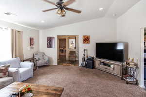 Living room with ceiling fan, dark colored carpet, vaulted ceiling, and washer / clothes dryer