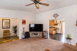 Living room with vaulted ceiling, dark tile floors, and ceiling fan