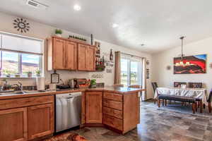 Kitchen with dark tile flooring, sink, dishwasher, and decorative light fixtures