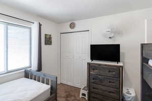 Bedroom with a closet, multiple windows, and dark carpet