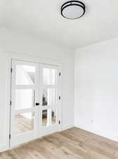 Unfurnished room featuring french doors and light wood-type flooring