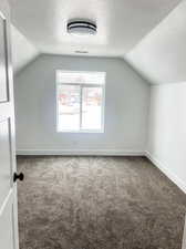 Bonus room with a textured ceiling, lofted ceiling, and carpet floors