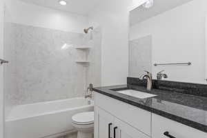 Full bathroom with tiled shower / bath, toilet, and vanity with extensive cabinet space