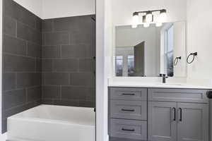 Bathroom with tiled shower / bath combo and vanity